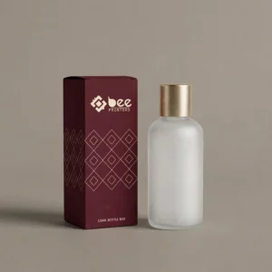 Closed burgundy box with a cream diamond lattice pattern and the Bee Printers logo standing beside a frosted bottle with a brushed gold cap on a taupe background, showing custom 120ml bottle boxes