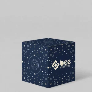 A closed navy cube box covered in a cream star and dot pattern on a light grey background, with the Bee Printers logo in cream on the lower right of the front face, showing custom 4 x 4 x 4 single wall cardboard boxes.