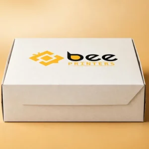 Custom bakery cake box closed with the Bee Printers logo printed on the lid on a warm golden-beige backdrop