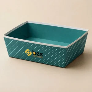 An empty teal polka-dot tray with a white rim and the Bee Printers logo on its front, an example of custom brand product trays on a beige background.