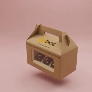 A floating kraft cardboard gable box with a front window showing dark chocolates and the Bee Printers logo on its top panel, shown as custom cardboard gable boxes against a pink background.