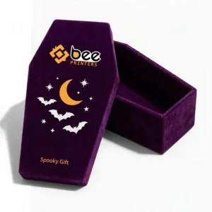 An open deep purple velvet coffin-shaped gift box with its empty base beside a lid printed with a moon, bats and stars and the Bee Printers logo at the top of the lid against a white background, showing custom coffin gift box.