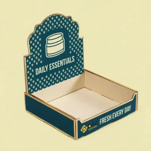 An empty dark teal counter display tray with a scalloped header showing a cream jar icon and Daily Essentials text, with Fresh Every Day and the Bee Printers logo on its front panel on a pale yellow background, showing custom counter display boxes wholesale.