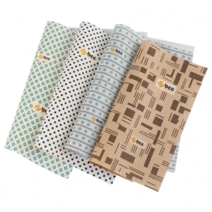 Four fanned butter paper sheets in teal diamond, navy dot, pale blue dot and kraft brown geometric patterns, each with a small Bee Printers logo, on a plain white background, showing custom custom butter paper