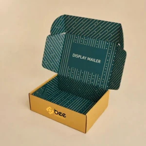 An open mustard-yellow mailer box with a teal striped interior and DISPLAY MAILER lettering on the lid, shown on a cream background as custom display mailer box wholesale.