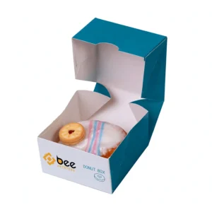 Open teal and white single box holding one white iced donut topped with a small jam biscuit on a plain white background, custom donut boxes with the Bee Printers logo on the front.