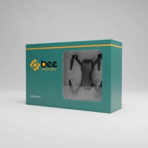 A closed teal box with a yellow top stripe and a clear front window revealing a black drone in a moulded tray on a light grey background, showing custom drone packaging boxes