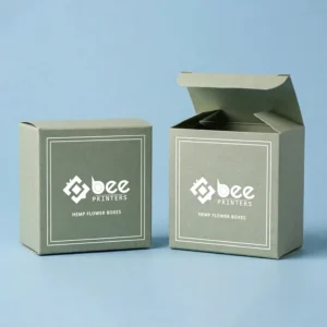 Two sage-green custom hemp flower boxes on a light blue background, one closed and one open and empty, both with a white framed Bee Printers logo on the front.