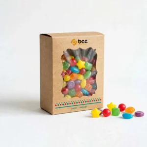 A closed brown kraft box with a scalloped clear window filled with colourful assorted candies and loose candies scattered in front on a white background, with the Bee Printers logo above the window on the front, showing custom kraft candy boxes.