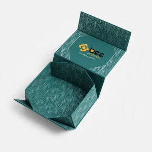 An open teal collapsible gift box with a white line pattern and a partly folded tray with the Bee Printers logo inside the lid on a white background, showing custom luxury collapsible boxes.