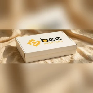 Closed custom rigid chipboard box in cream with the Bee Printers logo printed on the lid, warm golden-beige linen backdrop