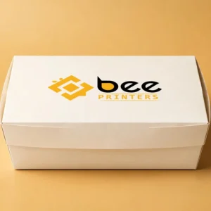 Custom sushi box in warm white with the Bee Printers logo printed on the closed lid, single hero box on a warm golden-beige studio backdrop