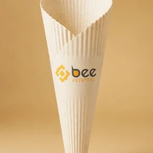 Custom waffle cone packaging sleeve in warm white standing upright with the Bee Printers logo printed on it, single hero sleeve on a warm golden-beige studio backdrop