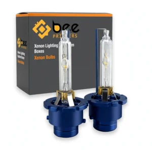 Closed dark grey box with an orange top stripe behind two xenon bulbs with blue bases on a plain white background, showing custom xenon lighting system boxes by Bee Printers.